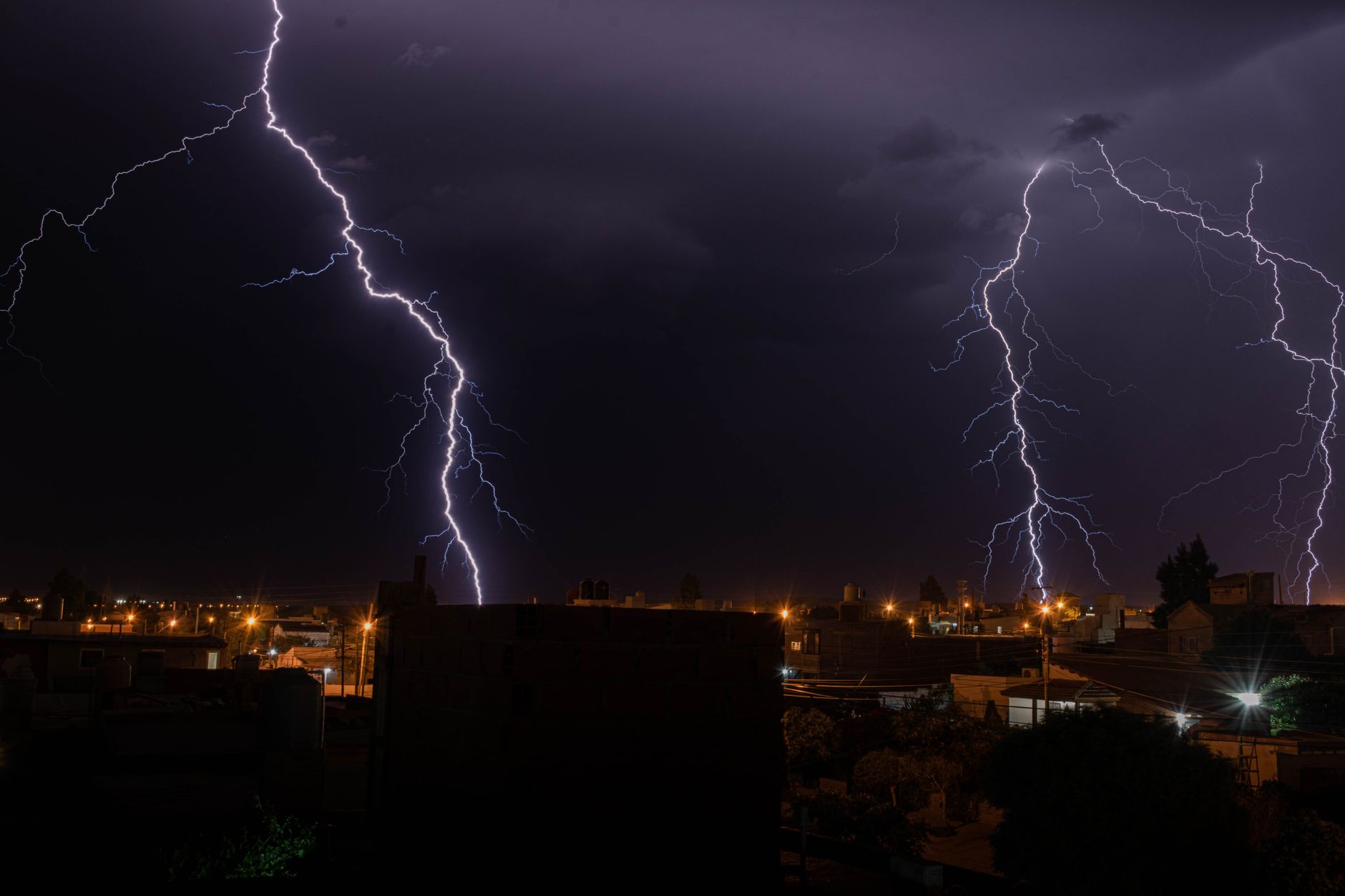 Nocna burza nad miastem z jasnymi błyskawicami