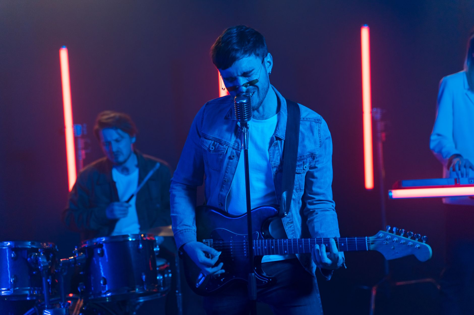 Zespół rockowy gra na żywo w neonowych światłach z gitarą i perkusją