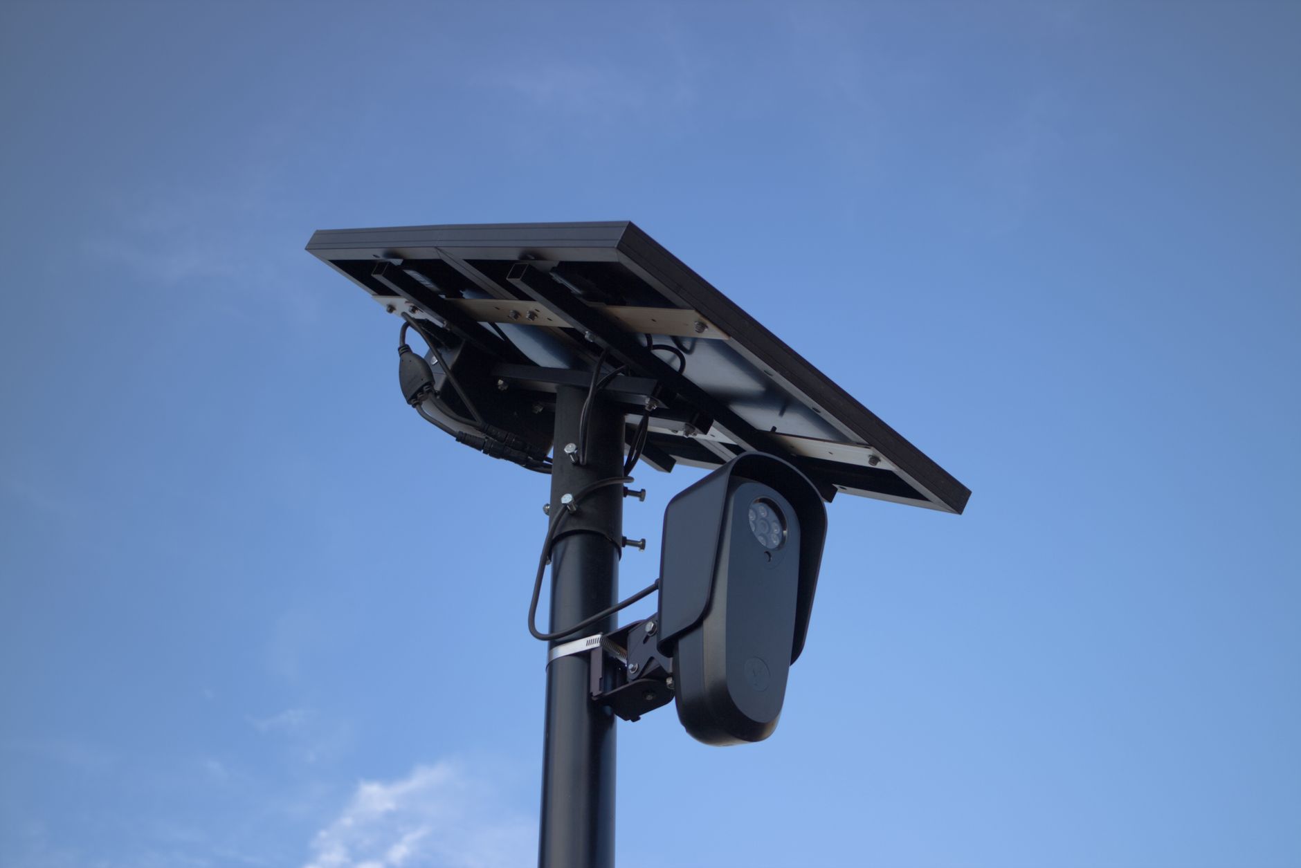 Kamera monitoringu z panelami fotowoltaicznymi na tle błękitnego nieba